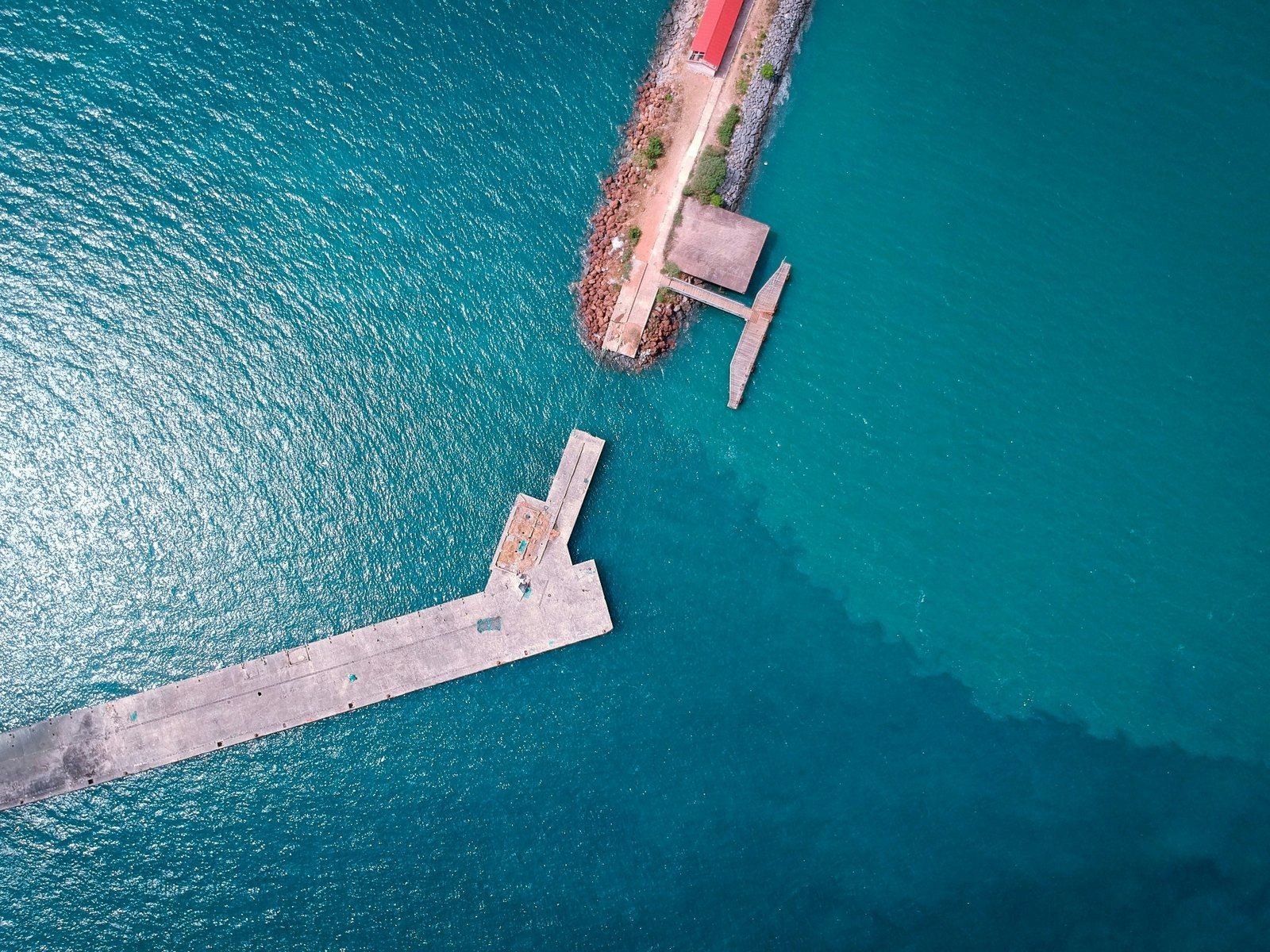 Vue aérienne d’une jetée sur une étendue d’eau turquoise.